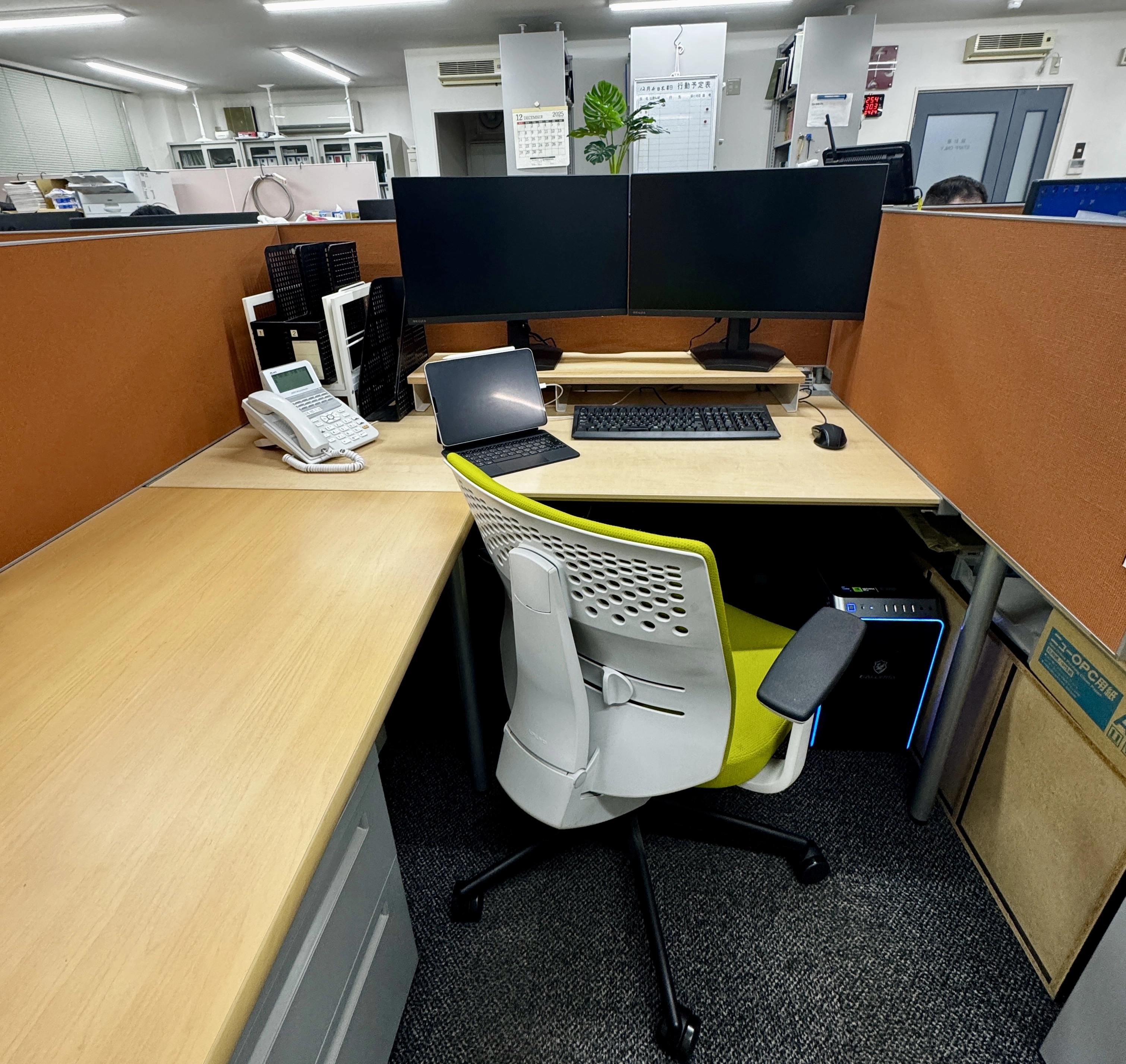 2F執務スペース　L型机で図面を広げながら作業ができ、パーテーションで区切られています。